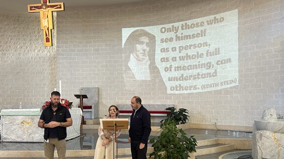 Three people stood on a platform behind a microphone.