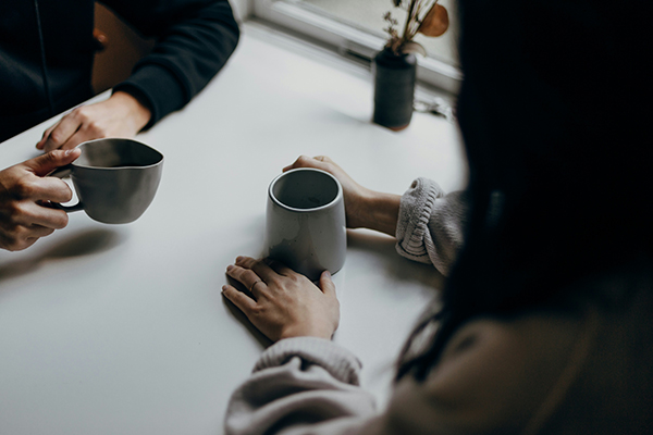 Two people holding cups of tea, only hands and arms showing